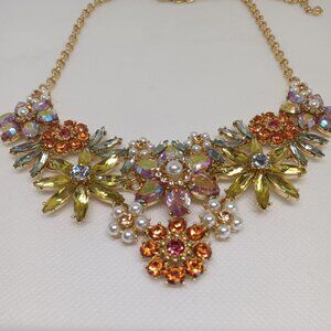 A crystal embellished floral necklace in  shades of orange, coral and yellow.